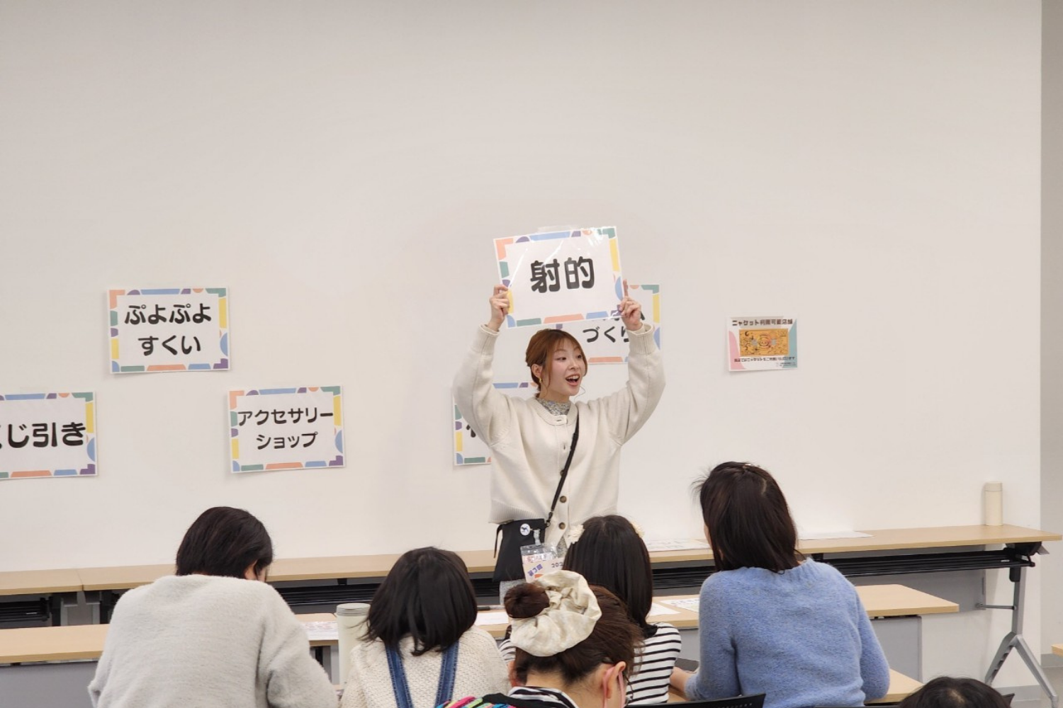 「射的」「ぷよぷよすくい」の看板を掲げる子どもたち