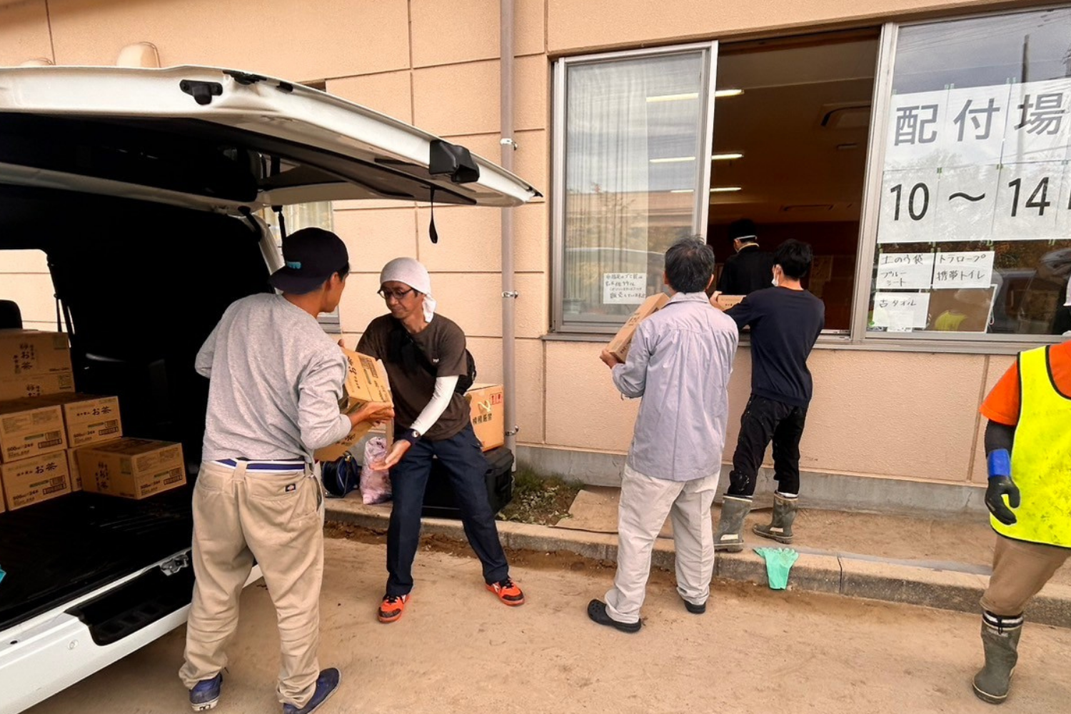 「配付場」の建物前で車から支援物資を降ろす様子