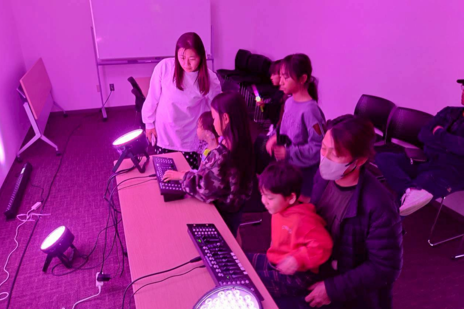 照明を落とした部屋で機材を操作する子どもたち