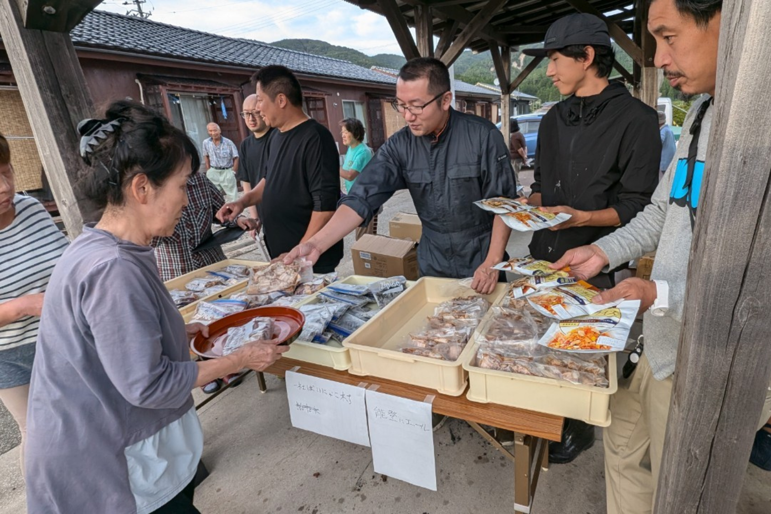 被災地の屋外で惣菜を配る様子