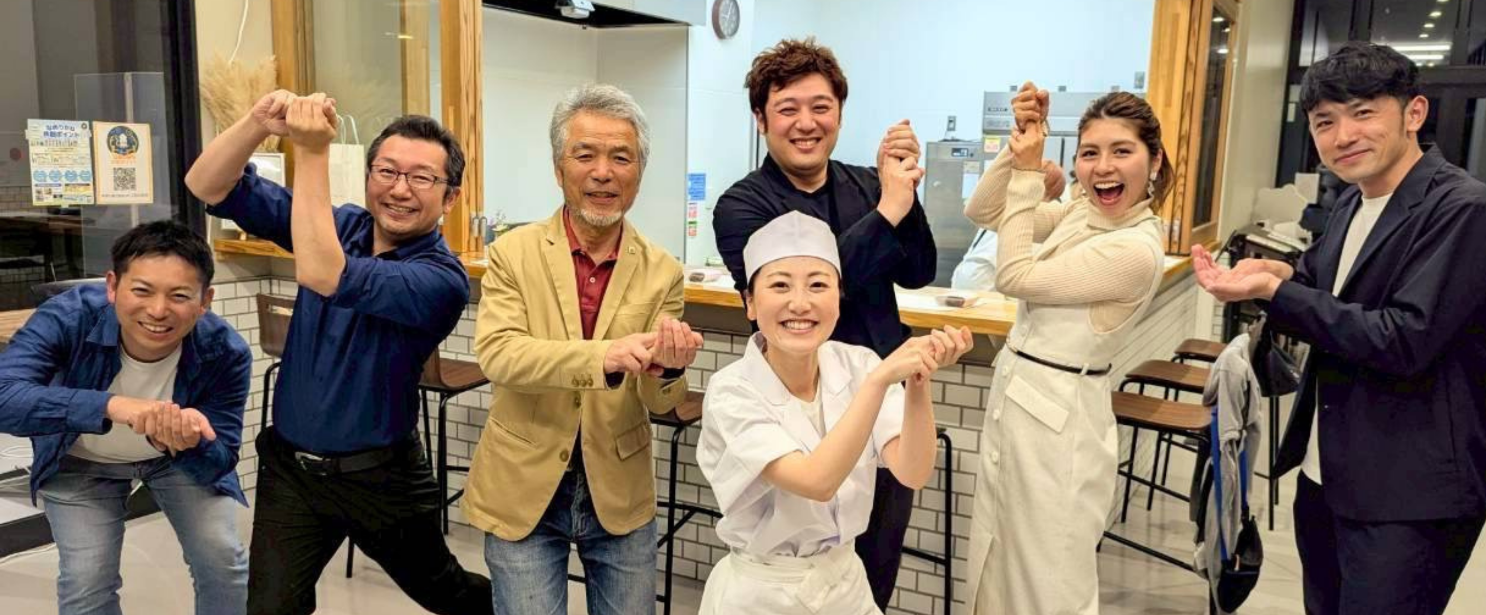 厨房前でポーズをとる大人たち