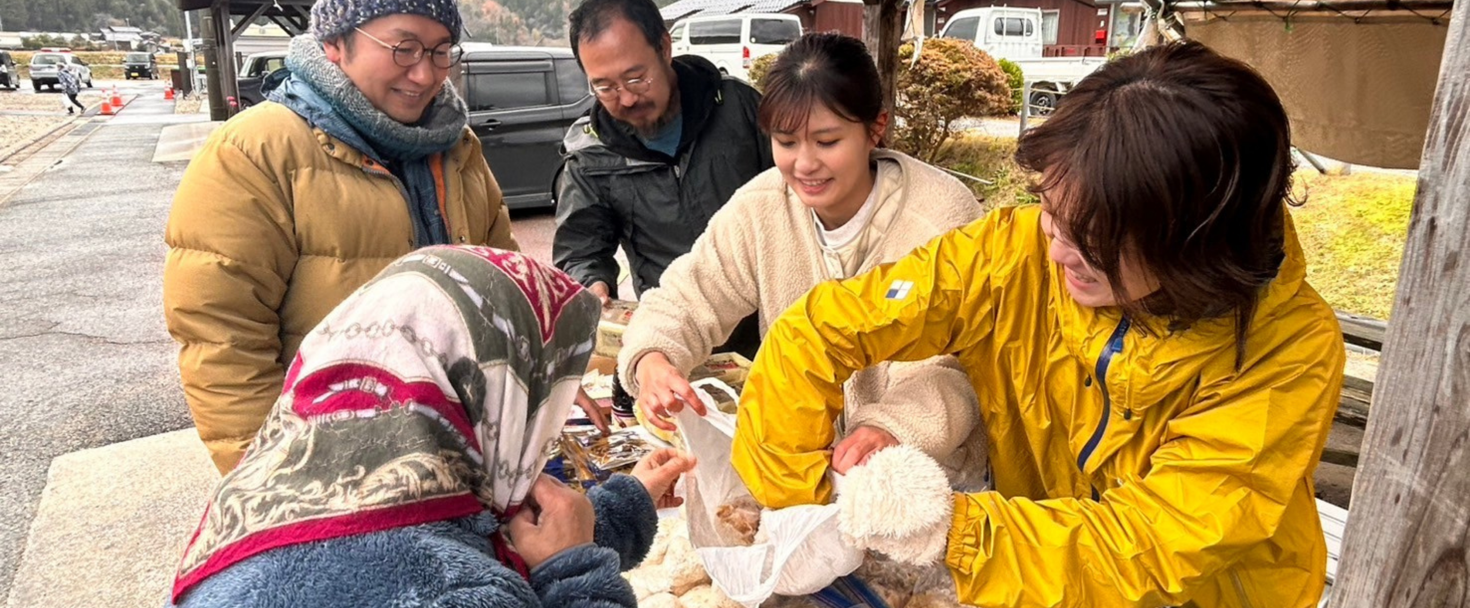 屋外のテントで支援物資を手渡すメンバー