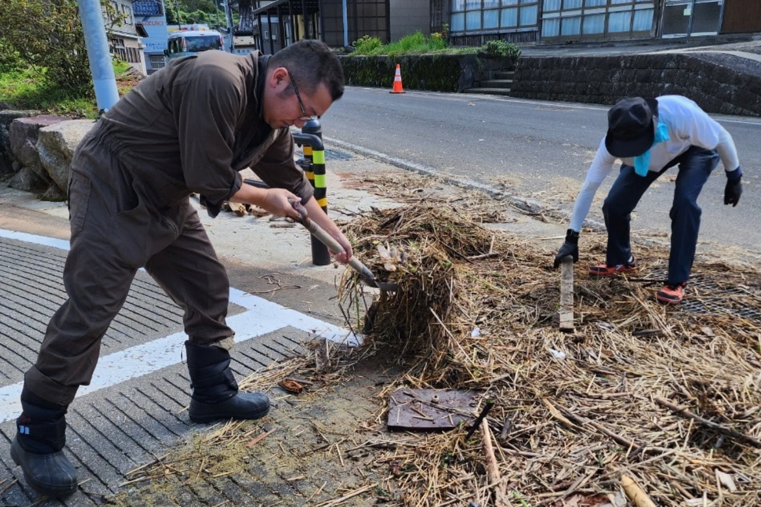 被災地の道路に堆積した土砂や流木をかき出す作業